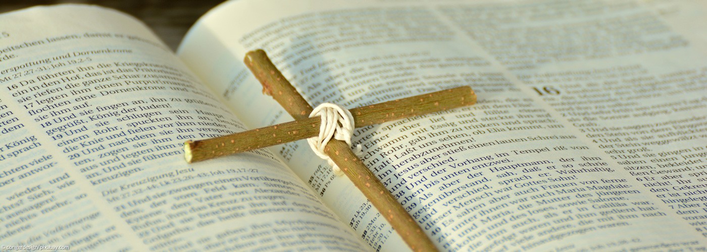 Kreuz aus zusammengebundenen Zweigen auf einer aufgeschlagenen Bibel